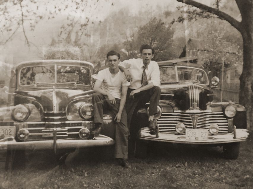historical photo of two men standing in front of a car